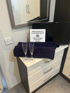 two wine glasses on a dresser with a sign on it at Olive Tree Lodge in West Thirston