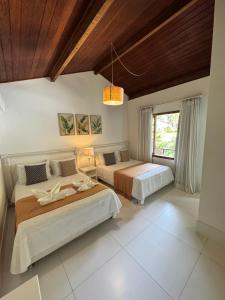 a bedroom with two beds and a wooden ceiling at Pousada Coisa e Tao in Arraial d'Ajuda +84 photos