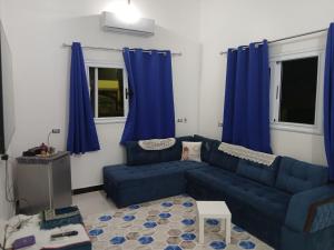a blue couch in a living room with blue curtains at Sunny said gust house in Al Aqālitah