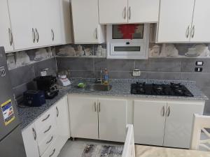 a kitchen with white cabinets and a sink at Sunny said gust house in Al Aqālitah