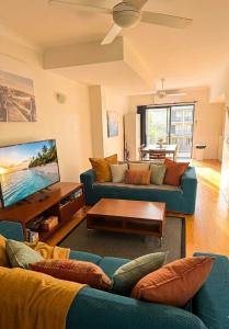 a living room with blue couches and a tv at Townhouse 7 - Located at FOOTPRINTS PRESTON BEACH RESORT in Preston Beach