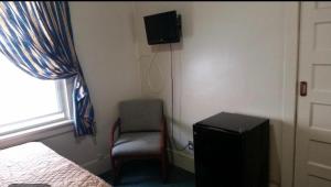 a bedroom with a bed and a chair and a television at A Voyageur's Guest House in Ottawa