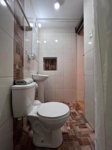 a bathroom with a white toilet and a sink at PAKARI Wasi in Cusco