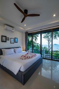 a bedroom with a large bed with a ceiling fan at Harbour View Villa in Ko Tao