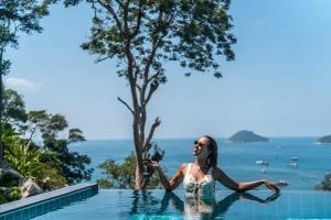 a woman sitting in the infinity pool at a resort at Harbour View Villa in Ko Tao
