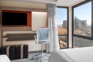 a hotel room with a bed and a chair and a large window at EVEN Hotel Brooklyn by IHG in Brooklyn