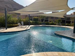 a swimming pool with an umbrella in a resort at Raha Inn Apartment in Aqaba +30 photos