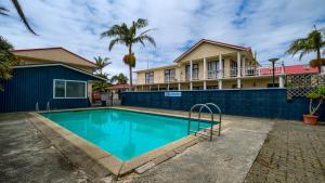a swimming pool in front of a house at Wayfarer Motel in Kaitaia
