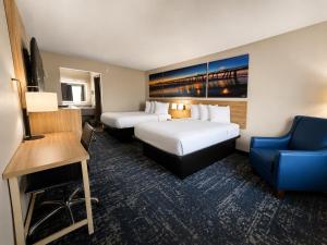 a hotel room with two beds and a blue chair at Days Inn by Wyndham Newberry South Carolina in Newberry