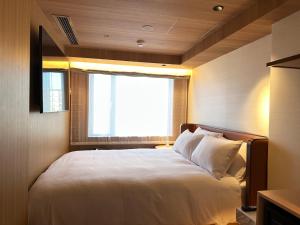 a bedroom with a large white bed with a window at KIORI Hotel Teramachi in Kyoto