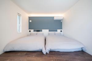 two beds in a room with white walls at YUTORELA 富津 indoor GOLF シミュレーションゴルフ付き l BBQ l ファミリー歓迎 in Futtsu