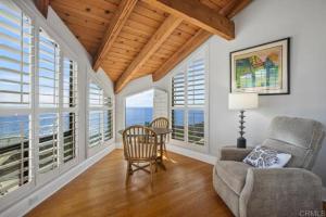 a living room with a chair and a table and windows at Solana Beach Resort in Solana Beach