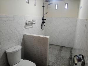 a white bathroom with a toilet and a sink at Naicha Green in Tetebatu
