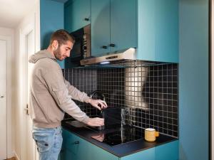 a man standing in a kitchen looking at a stove at Aparthotel Adagio access Hamburg in Hamburg +42 photos