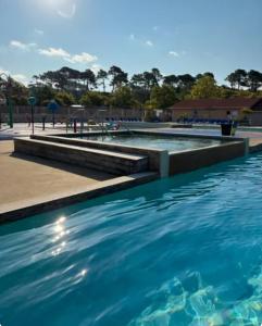 a swimming pool with blue water and steps at Mobil-home MJ in Seignosse