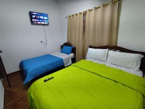 a bedroom with two beds with green sheets at Casa Manaba in Baños