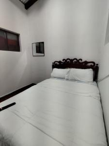 a bedroom with a white bed with a wooden headboard at Casa Manaba in Baños +3 photos