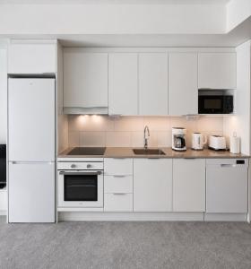 a white kitchen with white cabinets and appliances at Nord Heaven in Turku