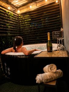 a woman in a bath tub with a bottle of wine at The Slothie's House in Fortuna