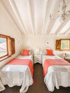 two beds in a white room with red pillows at Eirene Retreat - Quiet Riverside Escape in Upper Hutt