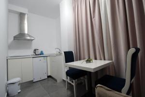 a room with a table and two chairs and a kitchen at Pigeon Cave Apartments in Ksamil