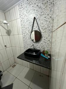 a bathroom with a sink and a mirror on the wall at Quarto próximo ao parque de exposição BR163 in Dourados