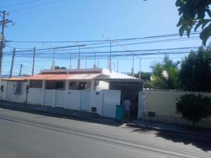 a man standing in front of a white house at Kitnet céu e mar in Saquarema