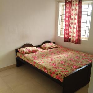a bedroom with a bed with a floral comforter and two windows at Shifa Home Near Apollo Sankara Nethralaya Main Hospital in Chennai
