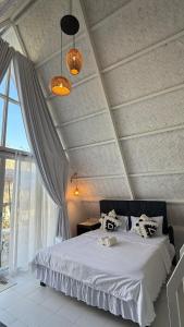 a bedroom with a bed with white sheets and a window at Cabin Corazon in Coron