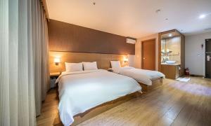 two beds in a hotel room with white sheets at Incheon Wolmido Stellamaris Hotel in Incheon