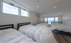 a bedroom with three beds with white sheets at Tabinoteitaku Y-beach in Tsuruoka