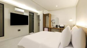a bedroom with a white bed with a television on the wall at 프라잇베리 호텔 in Chinhae +18 photos