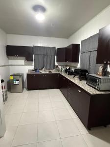 a kitchen with black cabinets and a white tile floor at Villa Rosita in San Carlos