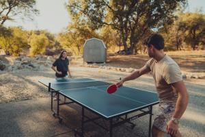 two people playing ping pong on a ping pong table at Sunset Site Boulder Bliss HotTub by Casa Oso in Ahwahnee