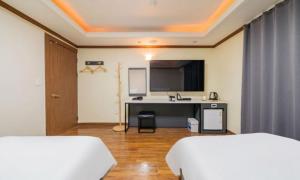 two beds in a room with a desk and a tv at Donghae Gloria Hotel in Donghae