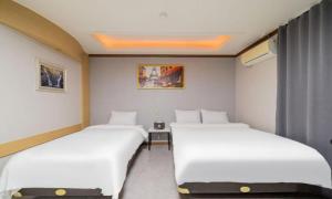 two beds in a small room with white sheets at Donghae Gloria Hotel in Donghae +33 photos