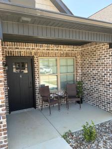a patio with two chairs and a table in front of a brick house at Brand new condo right off the interstate in Berea