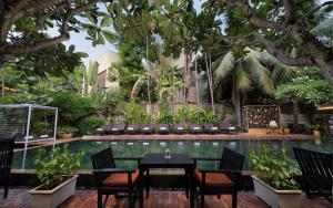 a patio with a table and chairs next to a pool at Home Indochine d'Angkor Hotel in Siem Reap