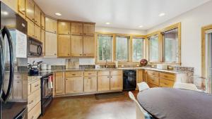 a large kitchen with wooden cabinets and a table at Rustic-Modern Cabin with Hot Tub Access in McCall