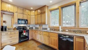 a kitchen with wooden cabinets and black appliances at Rustic-Modern Cabin with Hot Tub Access in McCall