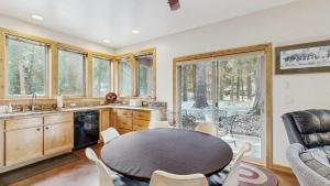 a dining room with a table and a kitchen with windows at Rustic-Modern Cabin with Hot Tub Access in McCall +20 photos