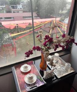 a table with a vase with flowers in a window at Le-Leisure Hotel in Prayagraj