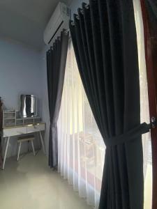 a room with a window with curtains and a desk at Sulis homestay in Kuta Lombok