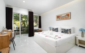 a white bedroom with a large bed and a desk at Home Indochine d'Angkor Hotel in Siem Reap