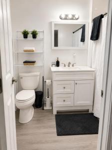 a white bathroom with a toilet and a sink at Spacious Modern 2BR Apartment Sleeps 6 in Niagara Falls