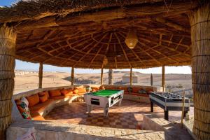 an outdoor seating area with a pool table in a straw umbrella at Agafay Pearl Camp Marrakech in Marrakesh
