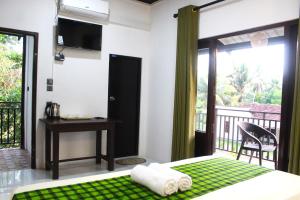 a bedroom with a bed and a desk and a balcony at The LeoEye Wilpattu in Pahala Maragahawewa
