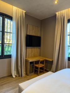 a bedroom with a bed and a desk with a television at Chateau Montchenot in Maipú