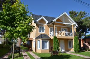 a large yellow house with a balcony at Picun Cuyen in Villa Gesell