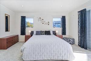 a bedroom with a large bed and two windows at Williamson Getaway - Top Whangamata Location in Whangamata